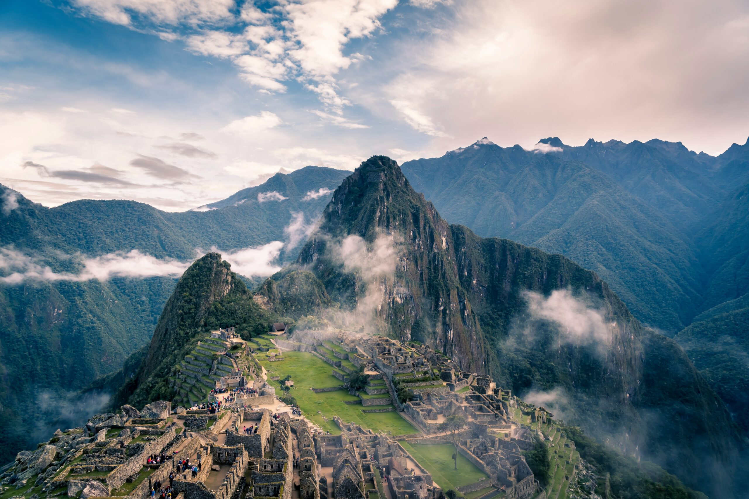 "A breathtaking view of Machu Picchu, the ancient Incan citadel in the Andes Mountains of Peru, surrounded by lush green peaks and misty clouds."