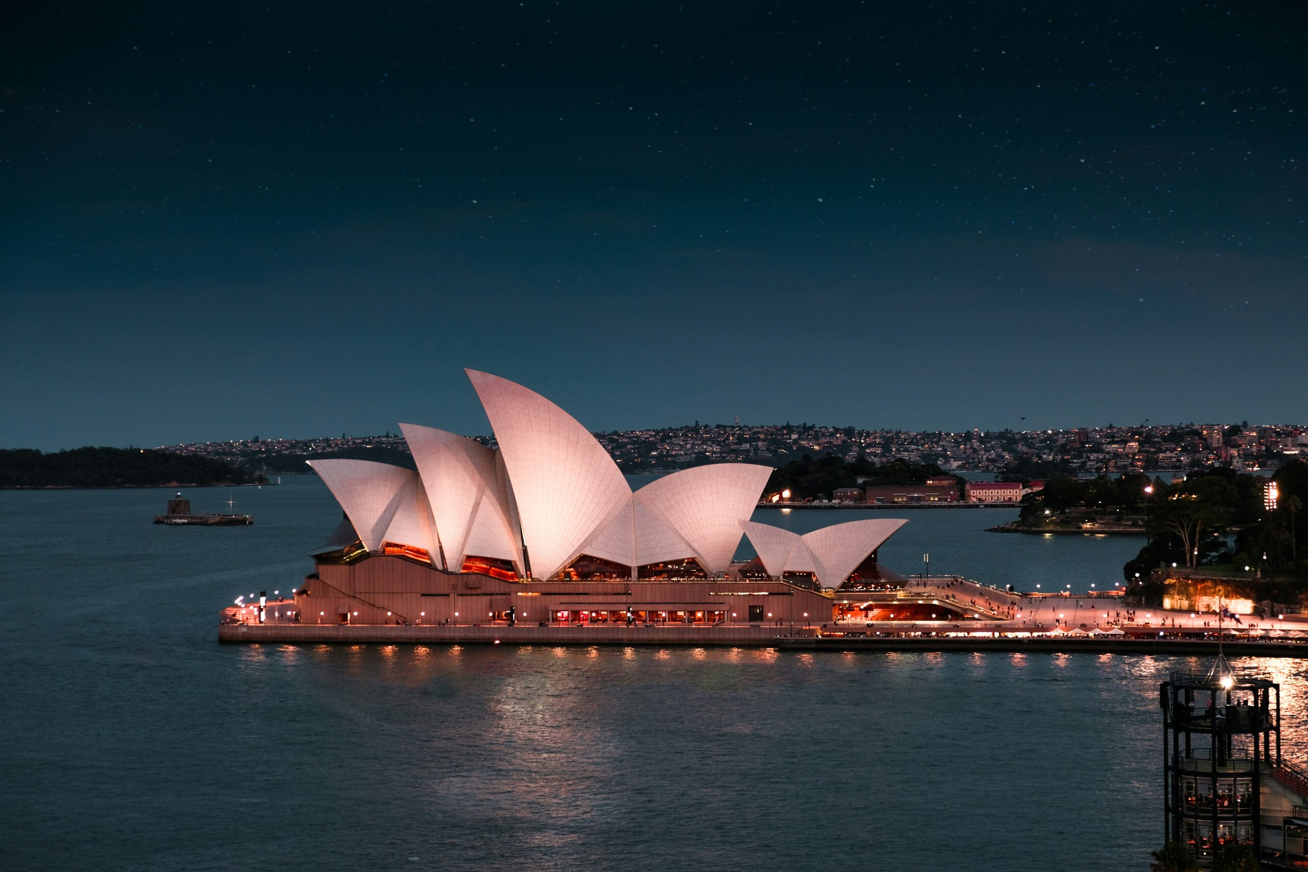 "A panoramic view of Sydney, Australia, featuring the iconic Sydney Opera House and Harbour Bridge against a vibrant sunset sky."