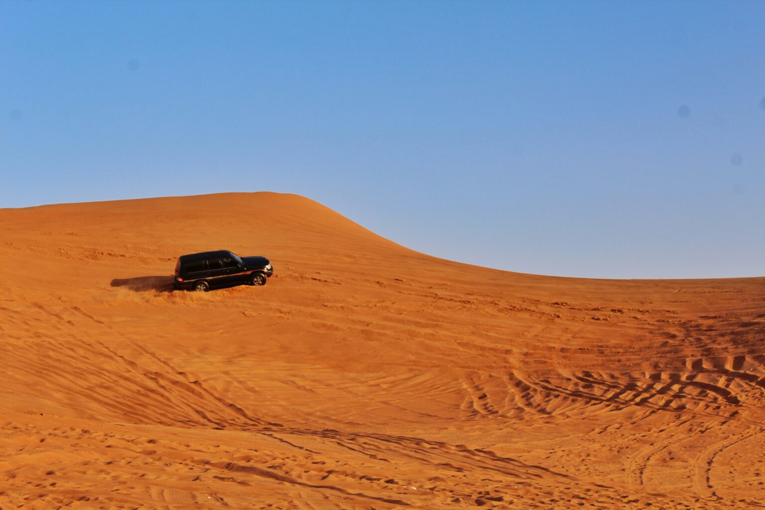 A breathtaking view of golden sand dunes in the Dubai desert under a clear blue sky