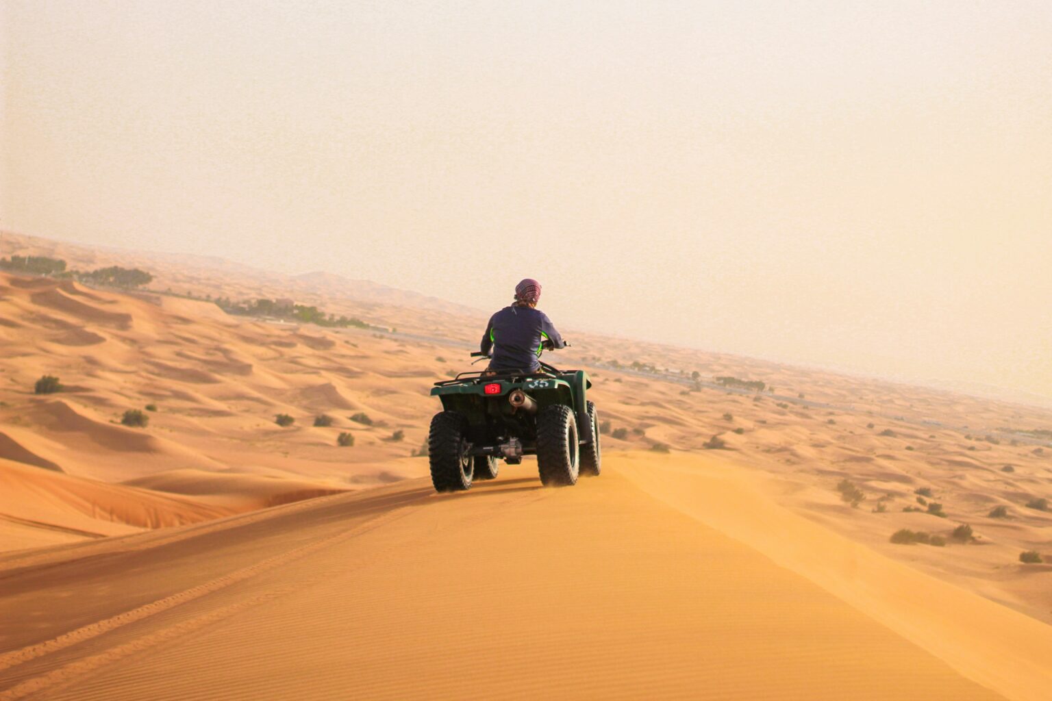 An off-road vehicle driving over sand dunes in the Dubai desert, with stunning natural scenery in the background